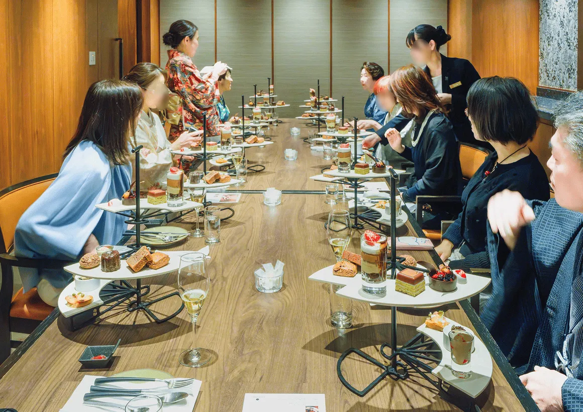  洗練された和モダンな個室で、アフタヌーンティースタイルのデザートを囲む参加者たち。上質な空間で特別な時間を過ごす様子。