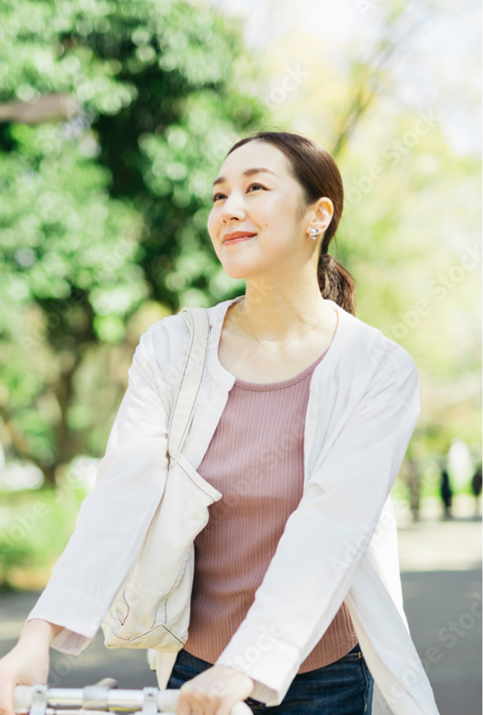 イメージ画像。木漏れ日の中、白い服を着た女性が明るい笑顔で振り向く。