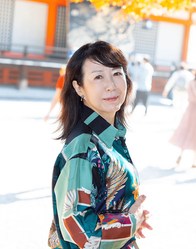 代表の内田早苗（うちださなえ）神社の境内で微笑んでいる